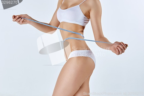 Image of Woman holding meter measuring perfect shape of her beautiful body 