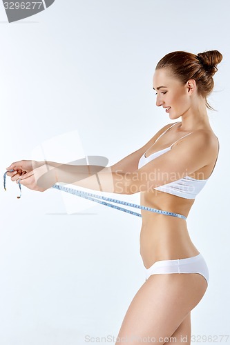 Image of Woman holding meter measuring perfect shape of her beautiful body 