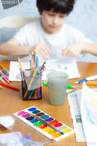 Image of palette with paints, crayons and young artist