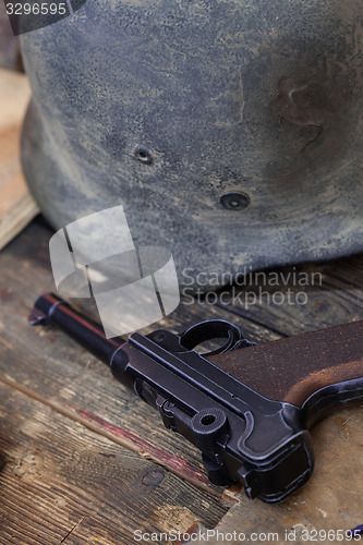 Image of pistol Parabellum and vintage German soldier helmet