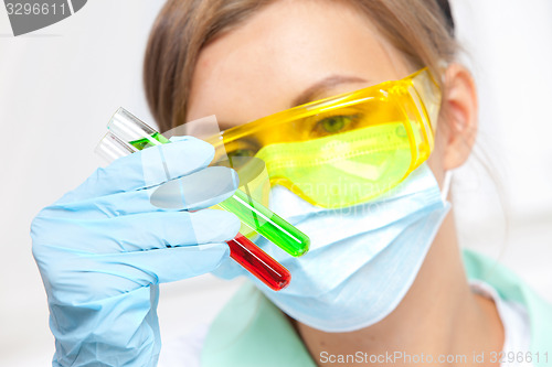 Image of doctor in a mask examines test tubes