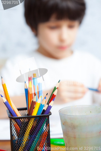 Image of colored pencils for drawing in pencil holders and the child on b
