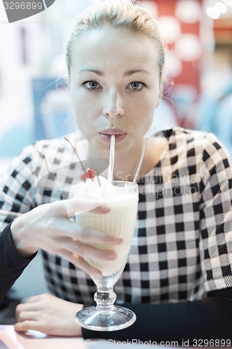 Image of Woman drinking milk shake in diner.