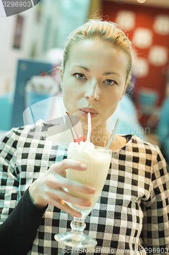 Image of Woman drinking milk shake in diner.