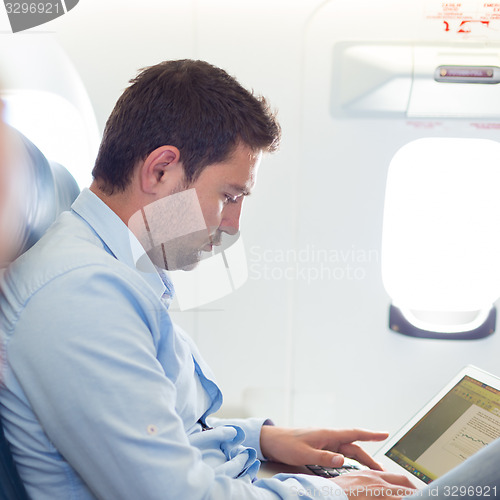 Image of Businessman working with laptop on airplane.