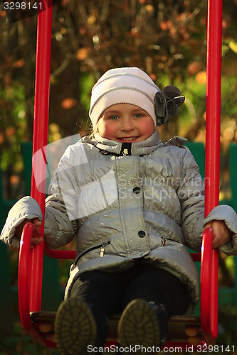 Image of little girl plays on the swing