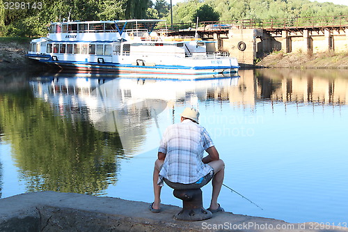 Image of fisherman sitting and fishing in the city river