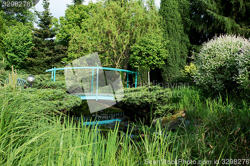 Image of small green footbridge over a pond