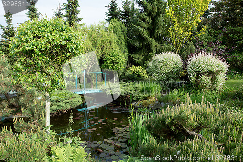 Image of small green footbridge over a pond