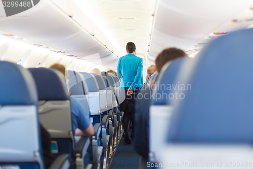 Image of Interior of airplane with stewardess walking the aisle.