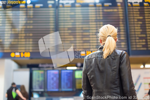 Image of Female traveller checking flight departures board.