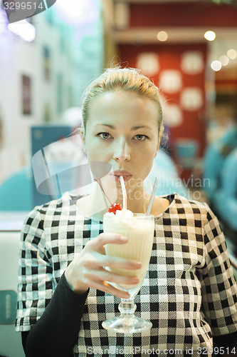 Image of Woman drinking milk shake in diner.