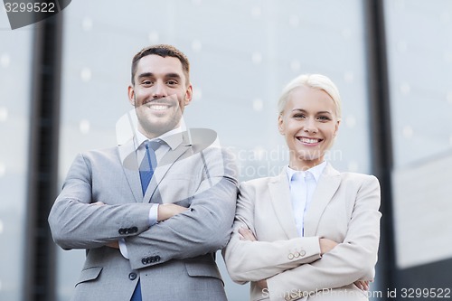 Image of smiling businessman and businesswoman outdoors