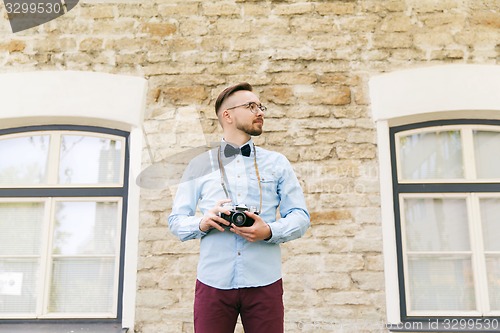 Image of young hipster man with film camera in city