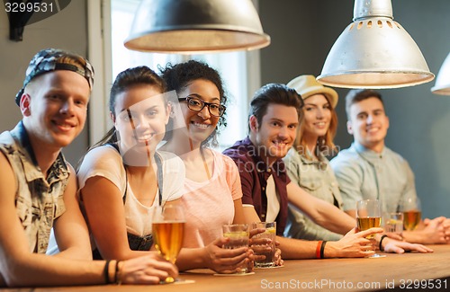 Image of happy friends drinking beer and cocktails at bar