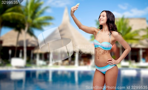 Image of woman in swimsuit taking selfie with smatphone