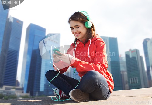 Image of happy young woman with smartphone and headphones