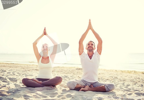 Image of smiling couple making yoga exercises outdoors