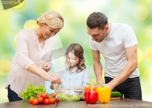 Image of happy family cooking vegetable salad for dinner