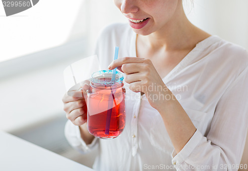 Image of woman drinking juice from glass mug with straw