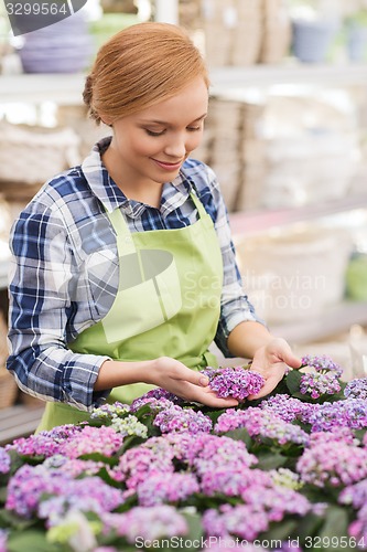 Image of happy woman taking care of flowers in greenhouse