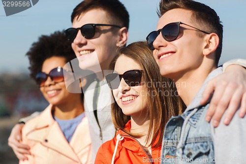 Image of happy teenage friends in shades hugging outdoors