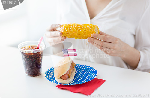 Image of woman hands holding corn with hot dog and cola