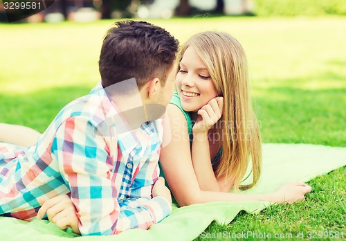 Image of smiling couple lying on blanket in park