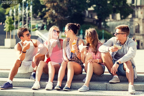 Image of group of smiling friends sitting on city square