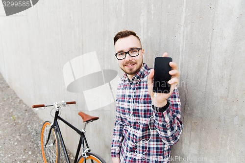 Image of hipster man in earphones with smartphone and bike