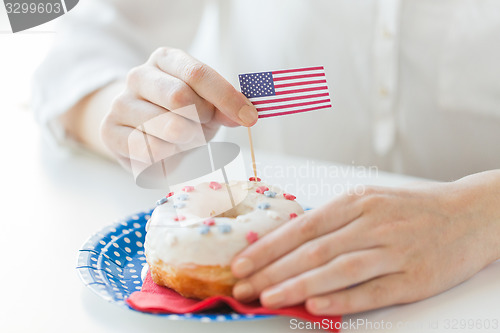 Image of female hands decorating donut with american flag