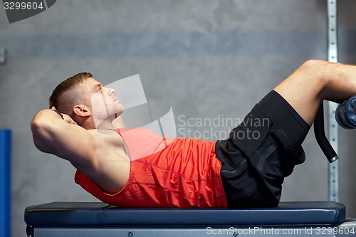 Image of young man making abdominal exercises in gym