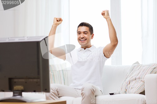 Image of smiling man watching sports at home