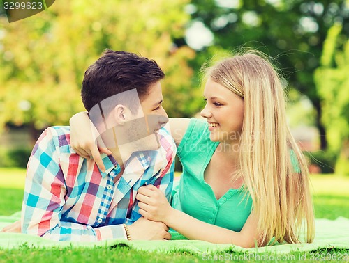 Image of smiling couple lying on blanket in park