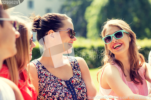 Image of group of smiling friends outdoors sitting in park