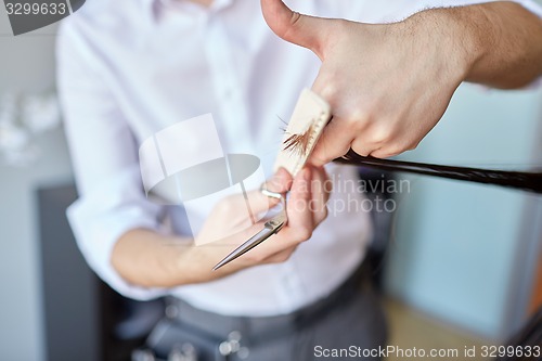 Image of male stylist hands cutting hair tips at salon