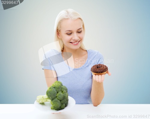 Image of smiling woman choosing between broccoli and donut