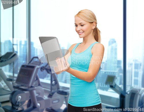 Image of smiling sporty woman with tablet pc in gym