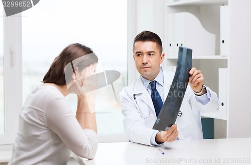 Image of smiling male doctor in white coat looking at x-ray