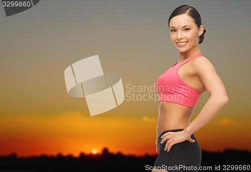 Image of happy asian woman outdoors over sunset skyline