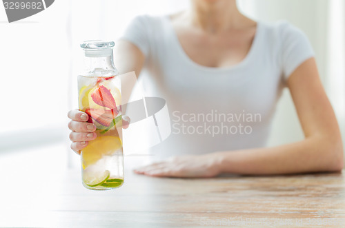 Image of close up of woman with fruit water in glass bottle