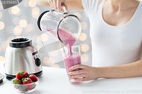 Image of close up of woman with blender pouring milk shake