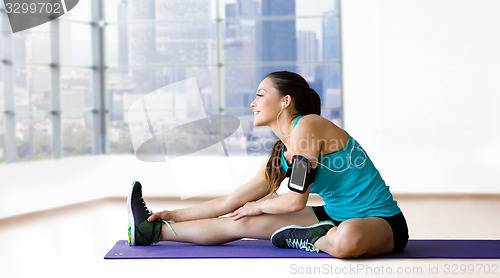 Image of smiling woman stretching leg on mat over gym