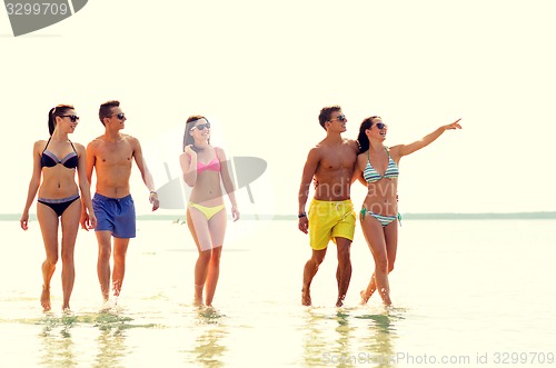 Image of smiling friends in sunglasses on summer beach