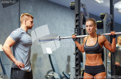 Image of man and woman with barbell flexing muscles in gym