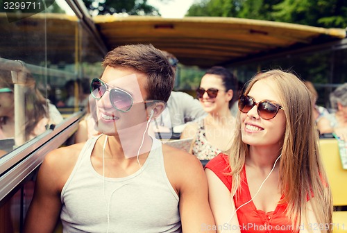 Image of smiling couple with earphones traveling by bus