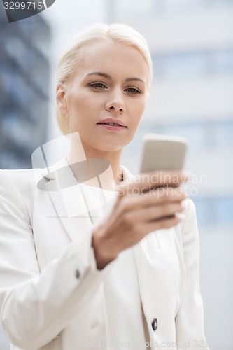 Image of serious businesswoman with smartphone outdoors