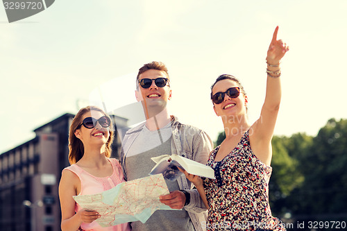Image of smiling friends with map and city guide outdoors