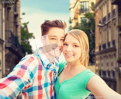 Image of smiling couple with smartphone in city background