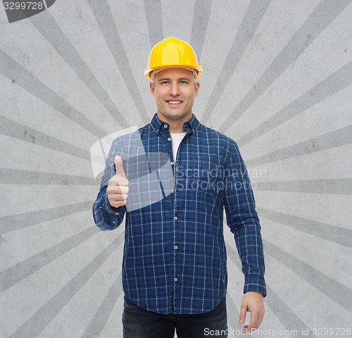 Image of smiling male builder in helmet showing thumbs up